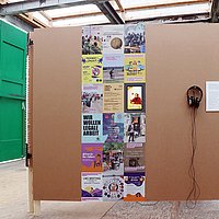 Bild der aktuellen Ausstellung ›Sorgende Stadt. Teil 2‹ im Pavillon mit einem Beitrag über ›Migrant Worker & Student Canteen‹ und ›Lieferando Workers Collective‹