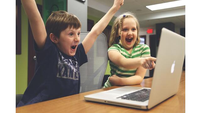 Zwei Kinder jubeln vor dem Laptop