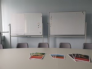 Blick auf einen Tisch mit Stühlen und Whiteboards im Hintergrund