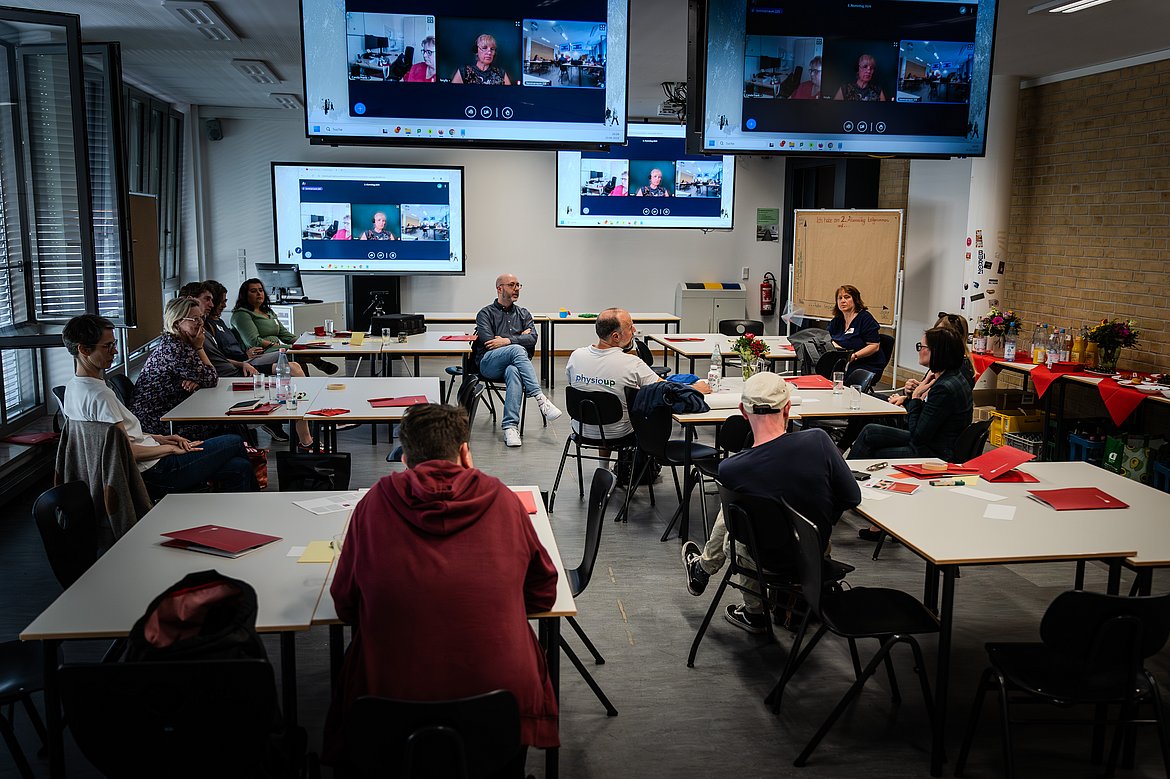 Eine Gruppe von Alumni nimmt an einem Workshop teil. Einige der Alumni nehmen aus der Ferne per Videokonferenz teil.