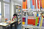 An einem Schreibtisch in der Hochschulbibliothek arbeitet ein Student mit Büchern.