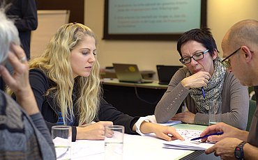 Vier Menschen sitzen in einer Diskussionsrunde am Tisch innerhalb des Master of Arts Studiengangs Klinische Sozialarbeit.