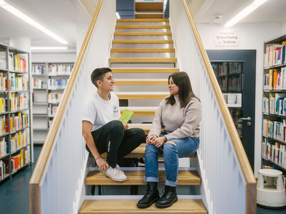 Zwei Personen sitzen auf der Treppe und unterhalten sich