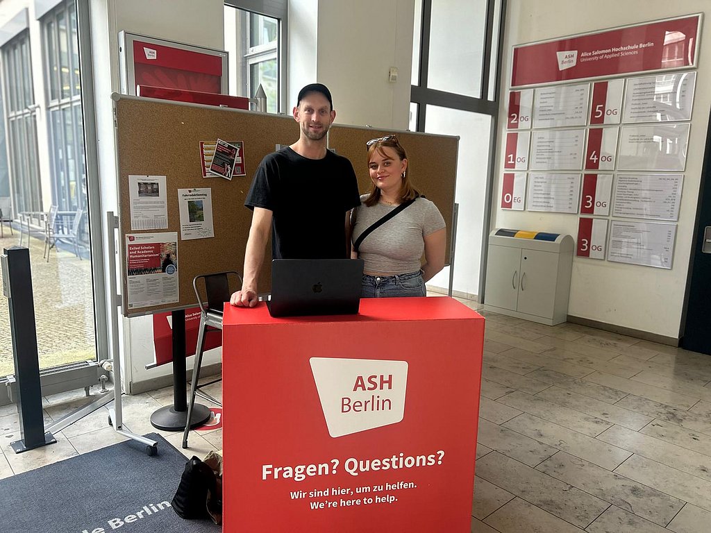 Die Studentischen Mitarbeiter_innen Leon und Laura am Infodesk.