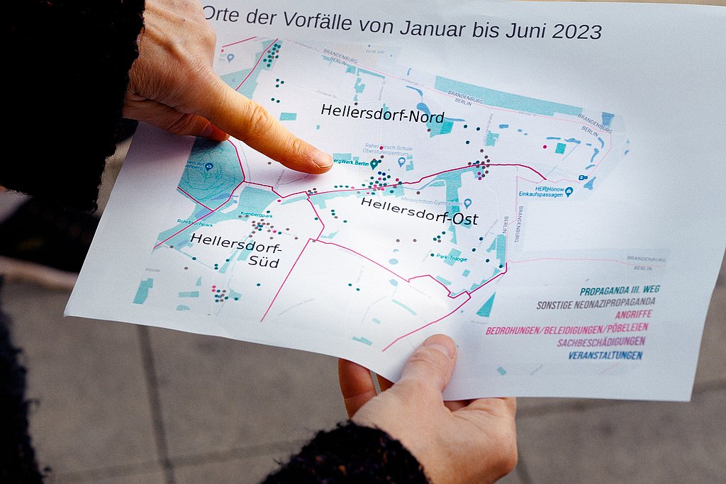 Eine Person hält eine Karte, auf der rechte Vorfälle in Hellersdorf von Januar bis Juni 2023 verzeichnet sind und deutet auf einen der Orte.