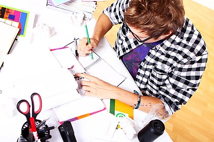 Ein Student sitzt am Schreibtisch und arbeitet, Aufnahme von oben