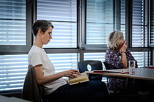 Eine Person mit kurzen Haaren und Brille schreibt während eines Workshops in ihr Notizbuch.