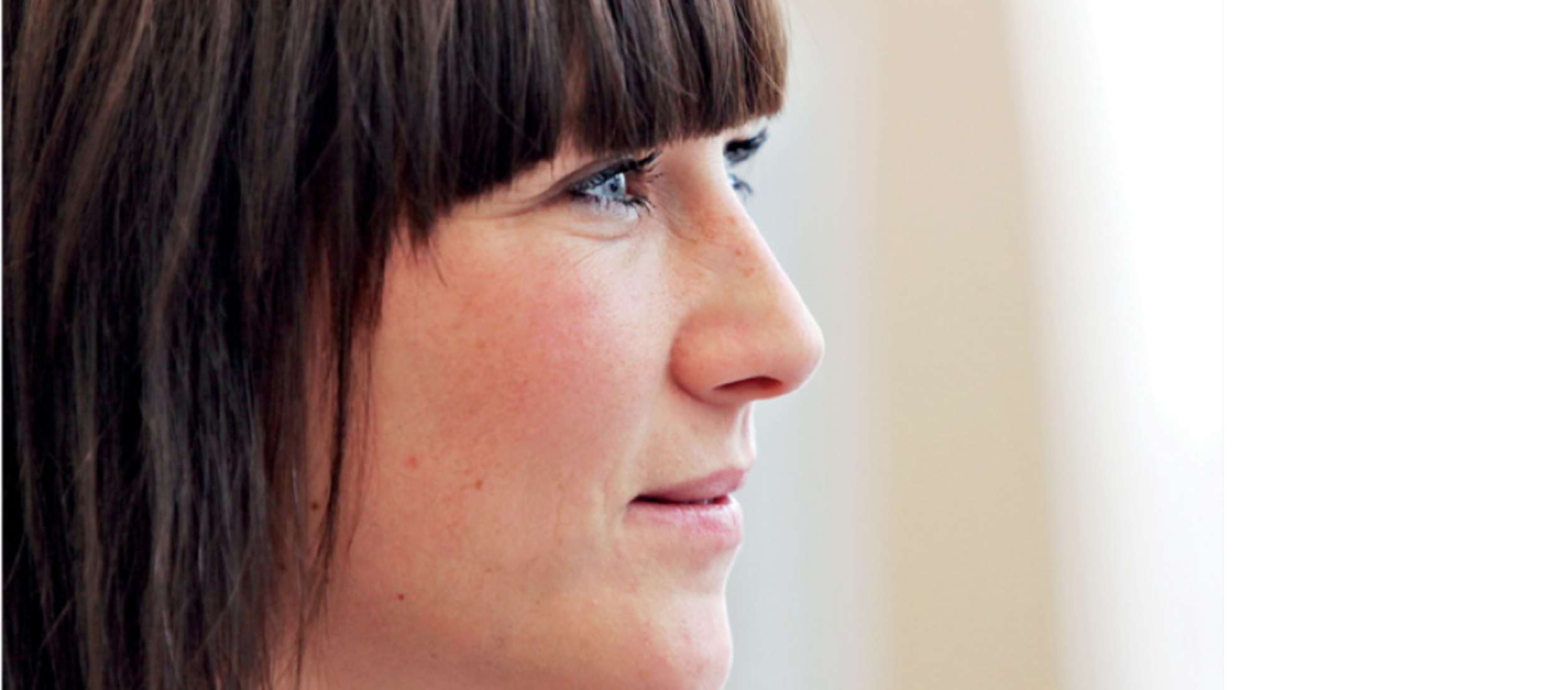 Eine junge Frau im Profil, die erwartungsvoll nach rechts schaut.